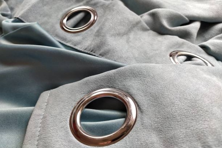 two metal eyelets on gray-blue velvet curtains.